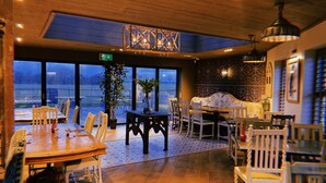 A restaurant with a view of the water, wooden tables and chairs, and a decorative ceiling. - The Queens at Horton (Telford)