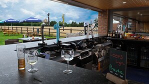 A bar area with a view of a grassy field and picnic tables. - The Queens at Horton (Telford)