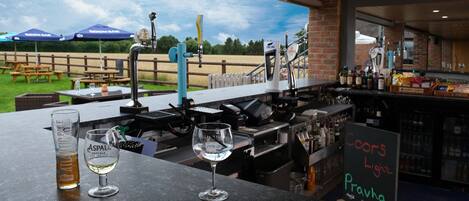 A bar area with a view of a grassy field and picnic tables.