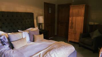 A bedroom with a large bed, a wooden wardrobe, a nightstand, and a chair.