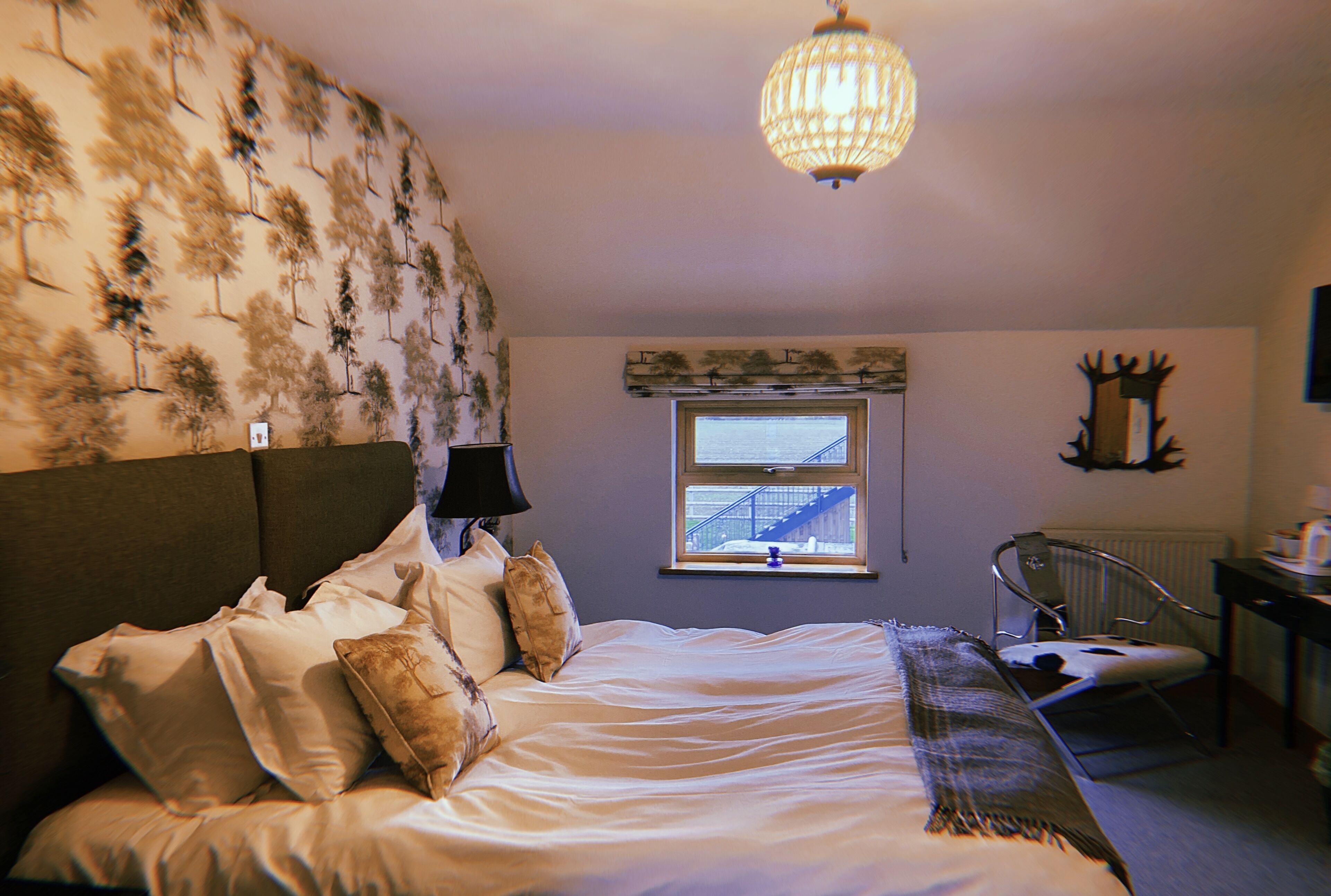 Une chambre à coucher avec un lit, une fenêtre donnant sur un immeuble, une chaise et un bureau.