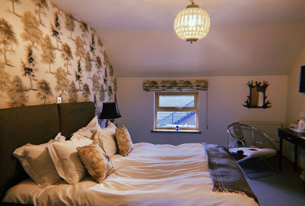 Une chambre à coucher avec un lit, une fenêtre donnant sur un immeuble, une chaise et un bureau.