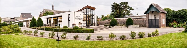 Un hotel moderno con fachada de vidrio, estructura de ladrillo y una pequeña capilla.
