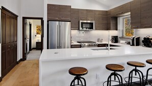 A modern kitchen with a central island, stainless steel appliances, and dark wood cabinetry. - Timberfalls 1905 3 Bedroom Condo by RedAwning (Vail)