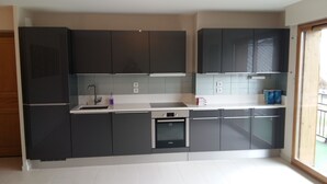 A modern kitchen with dark cabinets, a built-in oven, and a stainless steel sink.