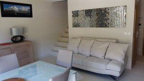 A living room with a sofa, a coffee table, a TV, and a staircase.