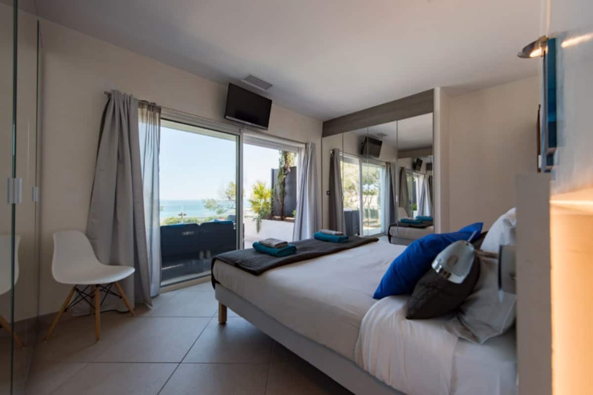 Une chambre d’hôtel moderne avec un grand lit, une chaise, une télévision et un balcon offrant une vue agréable.