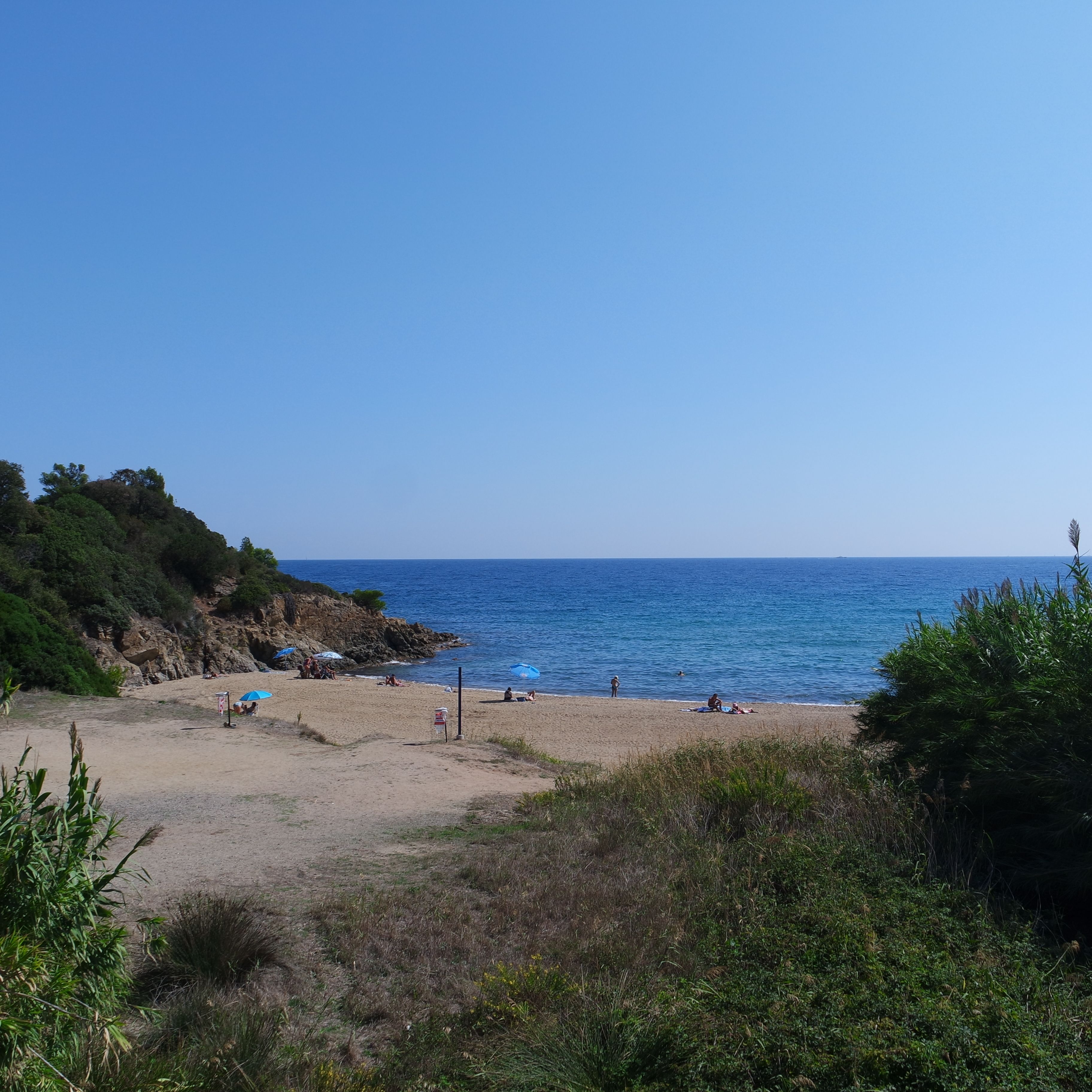 A beach with people sunbathing and swimming.