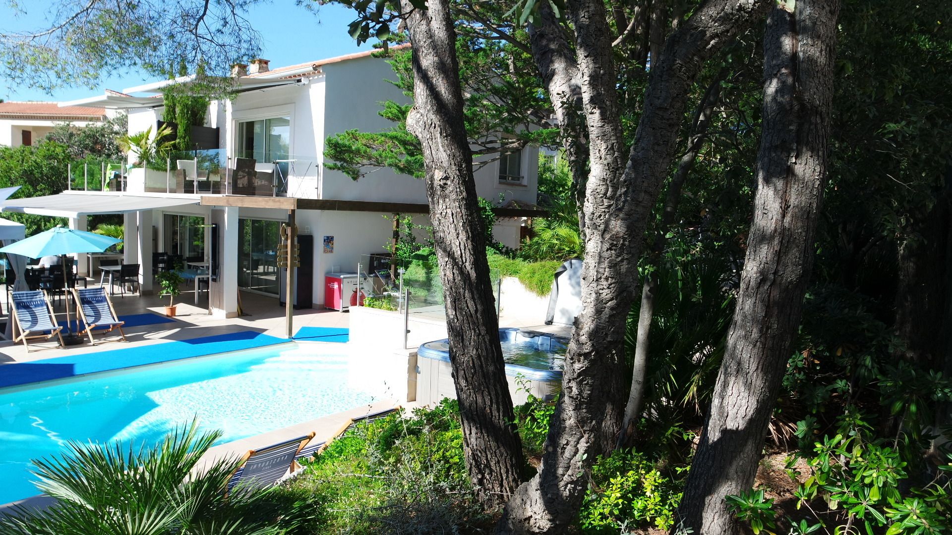 A modern hotel with a swimming pool, outdoor seating, and lush greenery.