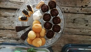 A glass plate with various pastries and desserts on a wooden surface.