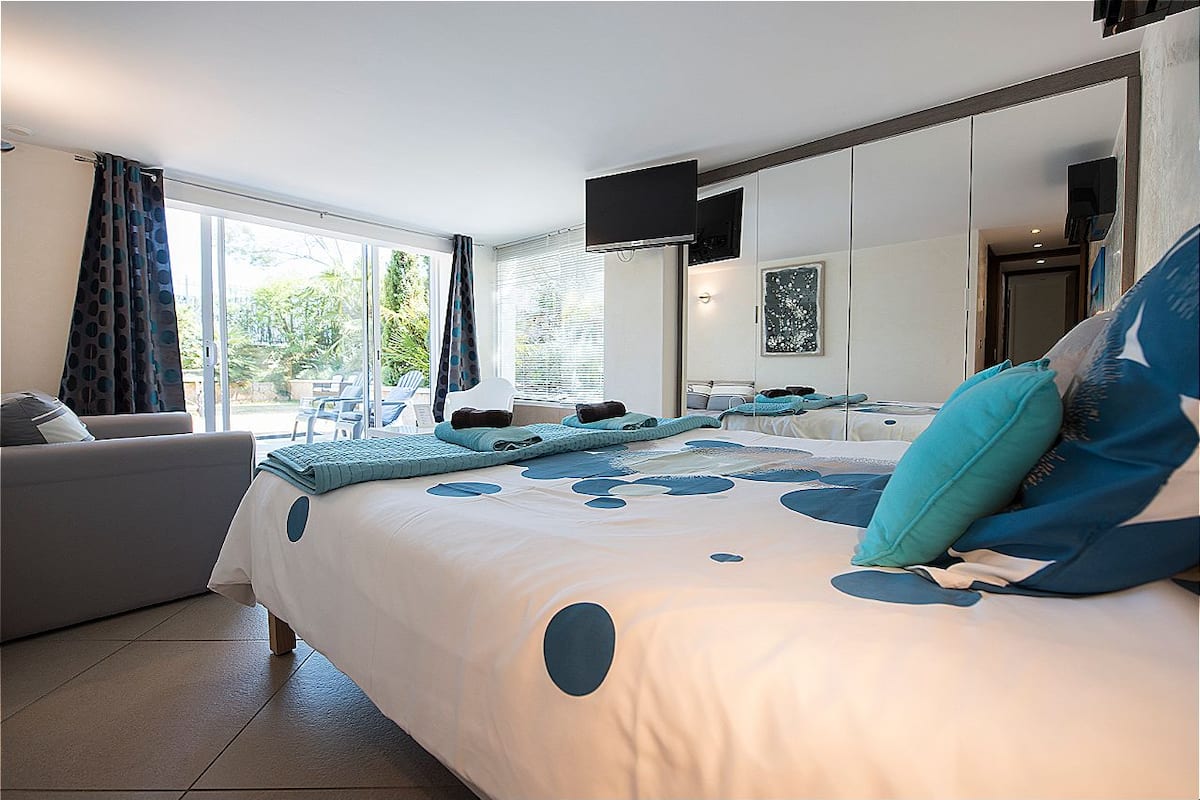 Une chambre moderne avec un grand lit, un canapé et un téléviseur fixé au mur.