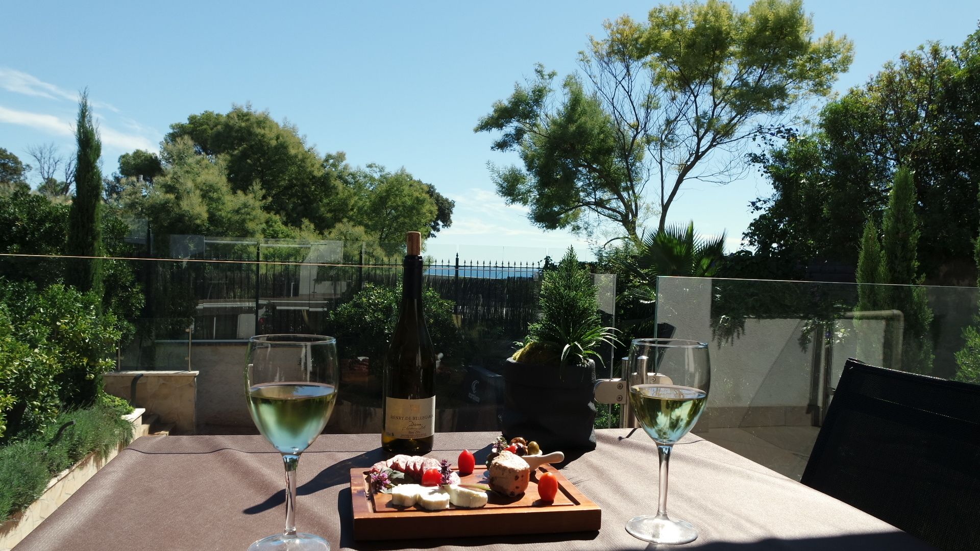 Une table avec une bouteille de vin, deux verres et une planche en bois sur laquelle sont disposés des aliments.