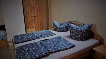 Ein Schlafzimmer mit einem hölzernen Bett, zwei Kissen, einem Nachttisch und einem Kleiderschrank.