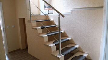 Un intérieur moderne avec un plancher en bois, un mur de couleur beige et un escalier dont les marches sont noires et la rampe est en métal.