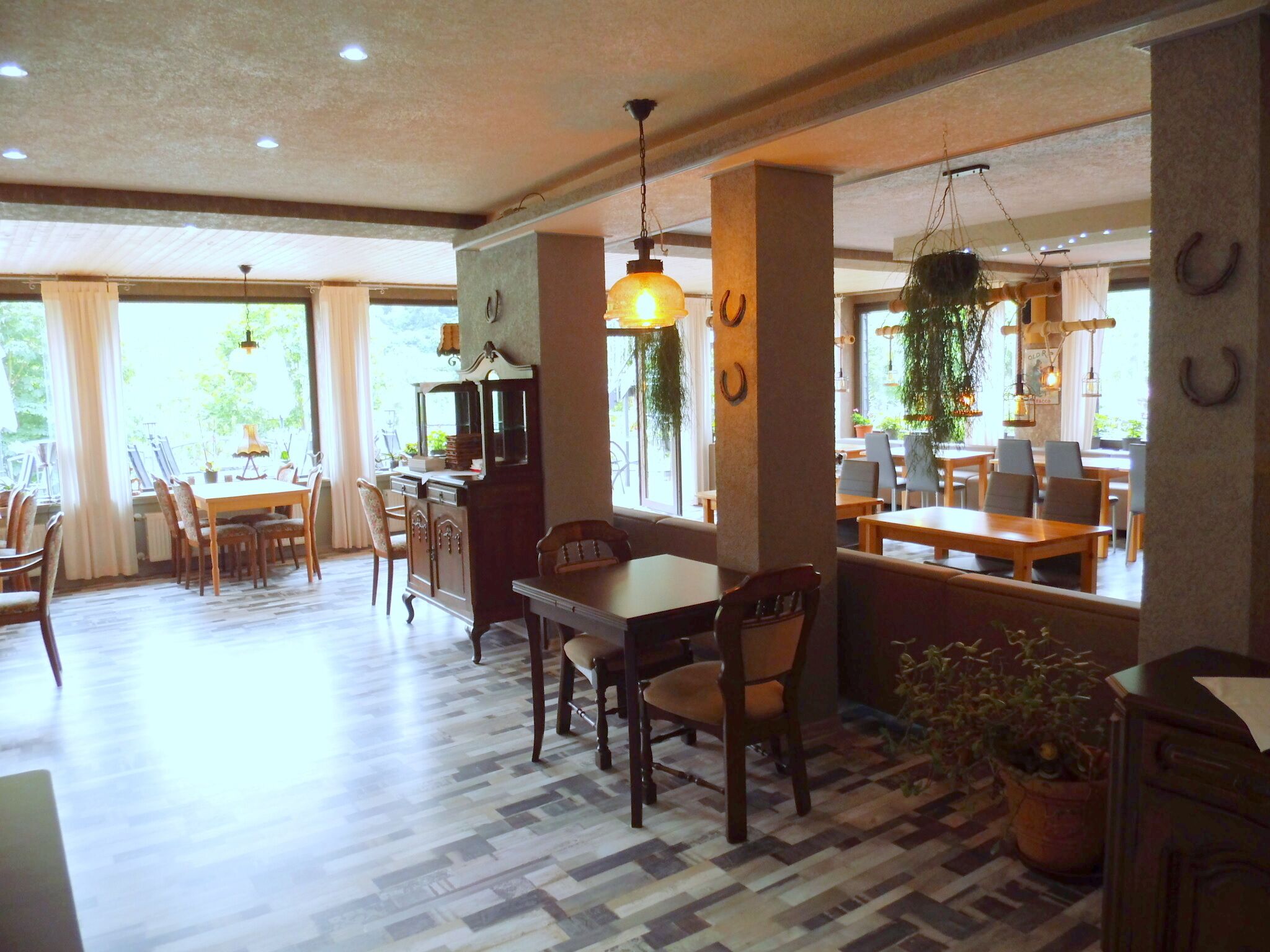 A spacious dining area with a wooden table and chairs, a bar area with a counter, and large windows allowing natural light.