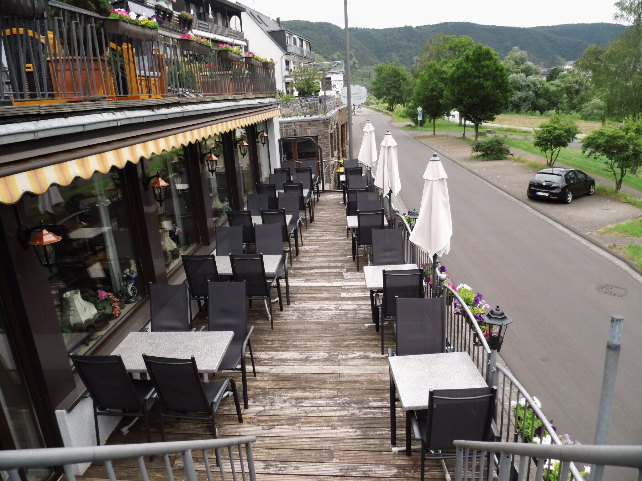 A restaurant with outdoor seating, a view of the street, and a mountain in the background.
