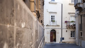 A narrow street with buildings on either side, featuring a door and windows with balconies. - Dimora di Ulisse (Syracuse)