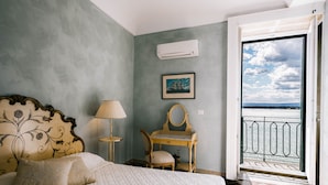 A bedroom with a bed, a desk, a chair, a lamp, a picture, and a view of the outside. - Dimora di Ulisse (Syracuse)