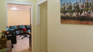 Een hal met een eetgedeelte, inclusief een tafel, stoelen, een bloevas en een schilderij aan de muur.