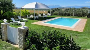 A pool area with a white umbrella, lounge chairs, and a view of the countryside. - I Tre Laghi Sant' Agnese - Rustic with pool, aircon (Pescara)