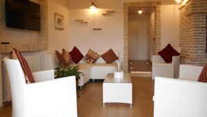 A modern living room with white sofas, a coffee table, and a TV mounted on the wall. - I Tre Laghi Sant' Agnese - Rustic with pool, aircon (Pescara)