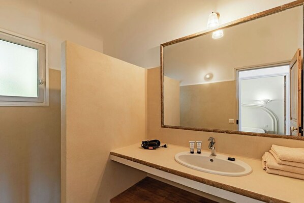 A bathroom with a large mirror, a sink, and a towel stack. - Résidence Pietra Di Sole (Porto-Vecchio)