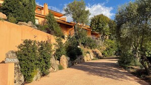 A dirt road leading to a building with a tiled roof, surrounded by greenery and rocks. - Résidence Pietra Di Sole (Porto-Vecchio)