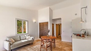 A modern living room with a sofa, a wooden dining table, and a kitchen area with a sink and countertop. - Résidence Pietra Di Sole (Porto-Vecchio)