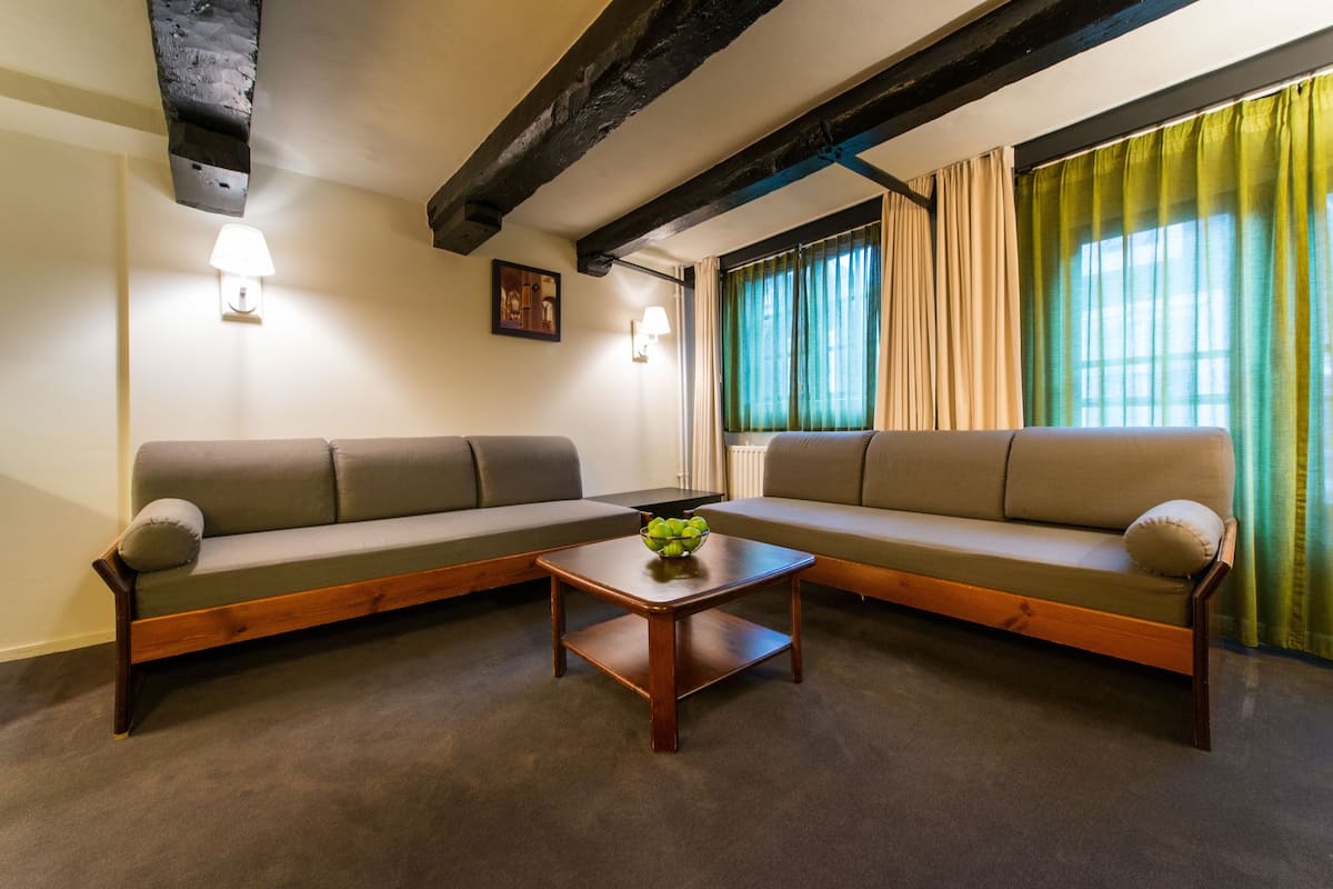 Una sala de estar con dos sofás, una mesa de centro y un ventanal con cortinas.