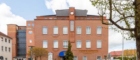 A red brick hotel with a sign reading "HOTEL & RESTAURANT" and a blue awning.