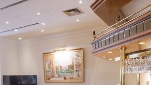 A bar area with a wooden counter, bar stools, and a television in the background. - Hotel Erbprinz (Ludwigslust)