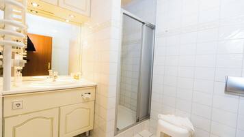 Un baño con tocador blanco, cabina de ducha de vidrio y inodoro blanco.