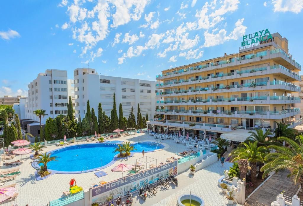 Ein Hotel mit Schwimmbad, mehreren Balkonen und blauem Himmel.