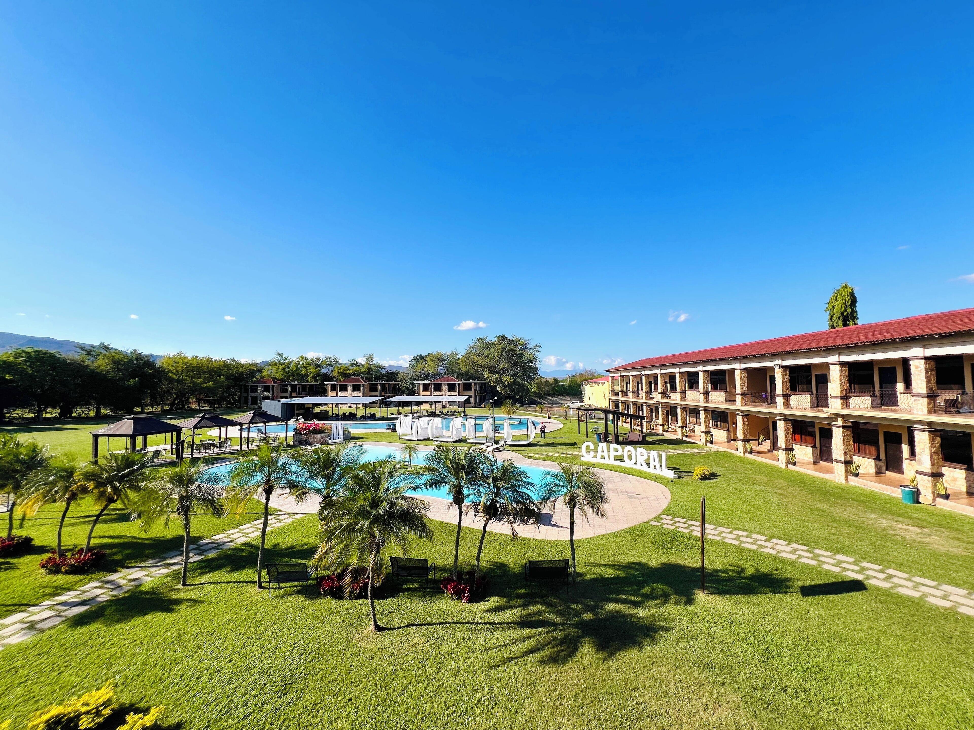 Un hotel con piscina, zona de estar al aire libre y césped bien cuidado.