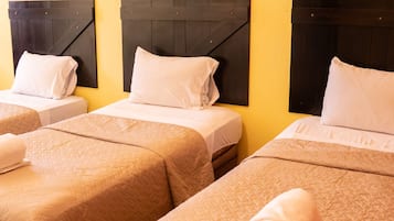 Camera d'albergo con due letti, ciascuno dotato di poggiatesta, una coperta trapuntata e un asciugamano arrotolato. Sulla parete sopra i letti sono presenti tre quadri incorniciati.