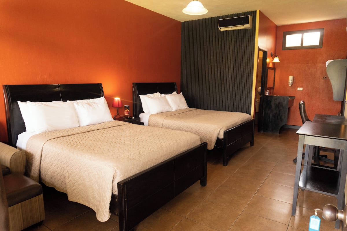 Een hotelkamer met twee bedden, een bureau en een stoel.