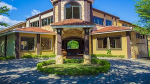 A large, two-story house with a stone facade, multiple windows, and a central archway. - Grand Caporal Hotel (Chiquimula)