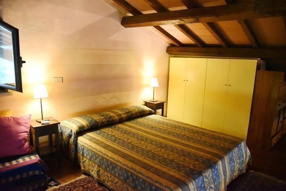 A bedroom with a bed, two bedside tables, a wardrobe, and a lamp.