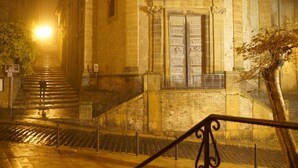Una escalera conduce a un edificio con un puerta grande y un balcón pequeño.
