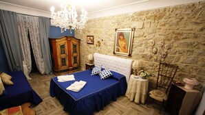 Un dormitorio con una cama grande, un aparador, una araña y una pared de piedra.