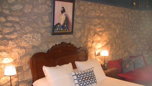 A bedroom with a stone wall, a wooden headboard, a bed with white bedding, two bedside lamps, and a framed picture on the wall. - Casa Xan de Pena (Vilarmaior)