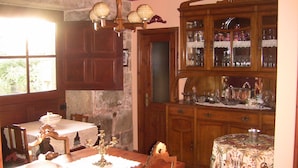 A dining area with a wooden table, chairs, a chandelier, and a cabinet with glassware. - Casa Xan de Pena (Vilarmaior)