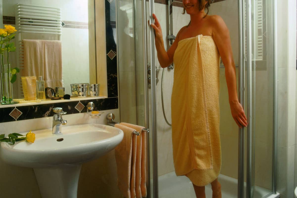 A bathroom with a glass-enclosed shower, a sink, and a mirror.