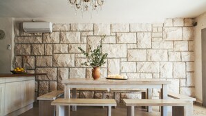 A kitchen with a stone wall, wooden table, benches, and a potted plant. - Seafront Villa in Bol - Prime Location  (Bol, island of Brac)