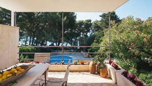An outdoor seating area with a pool, surrounded by trees and plants. - Seafront Villa in Bol - Prime Location  (Bol, island of Brac)