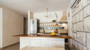 A kitchen with a wooden countertop, white cabinets, a stainless steel refrigerator, a built-in oven, and a stone wall. - Seafront Villa in Bol - Prime Location  (Bol, island of Brac)