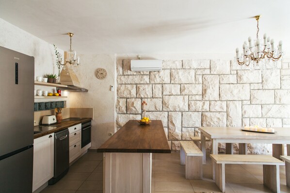 Una cocina moderna con pared de piedra, una isla de madera y un área de comedor con bancos.