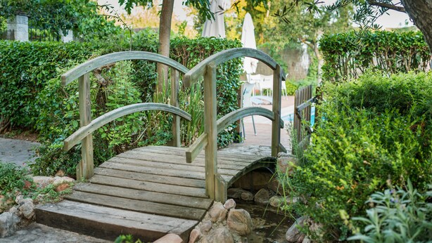 Een houten brug over een beekje in een tuin.