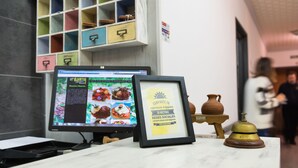 A reception desk with a computer monitor displaying a website, a framed sign, and a small bell on a stand.