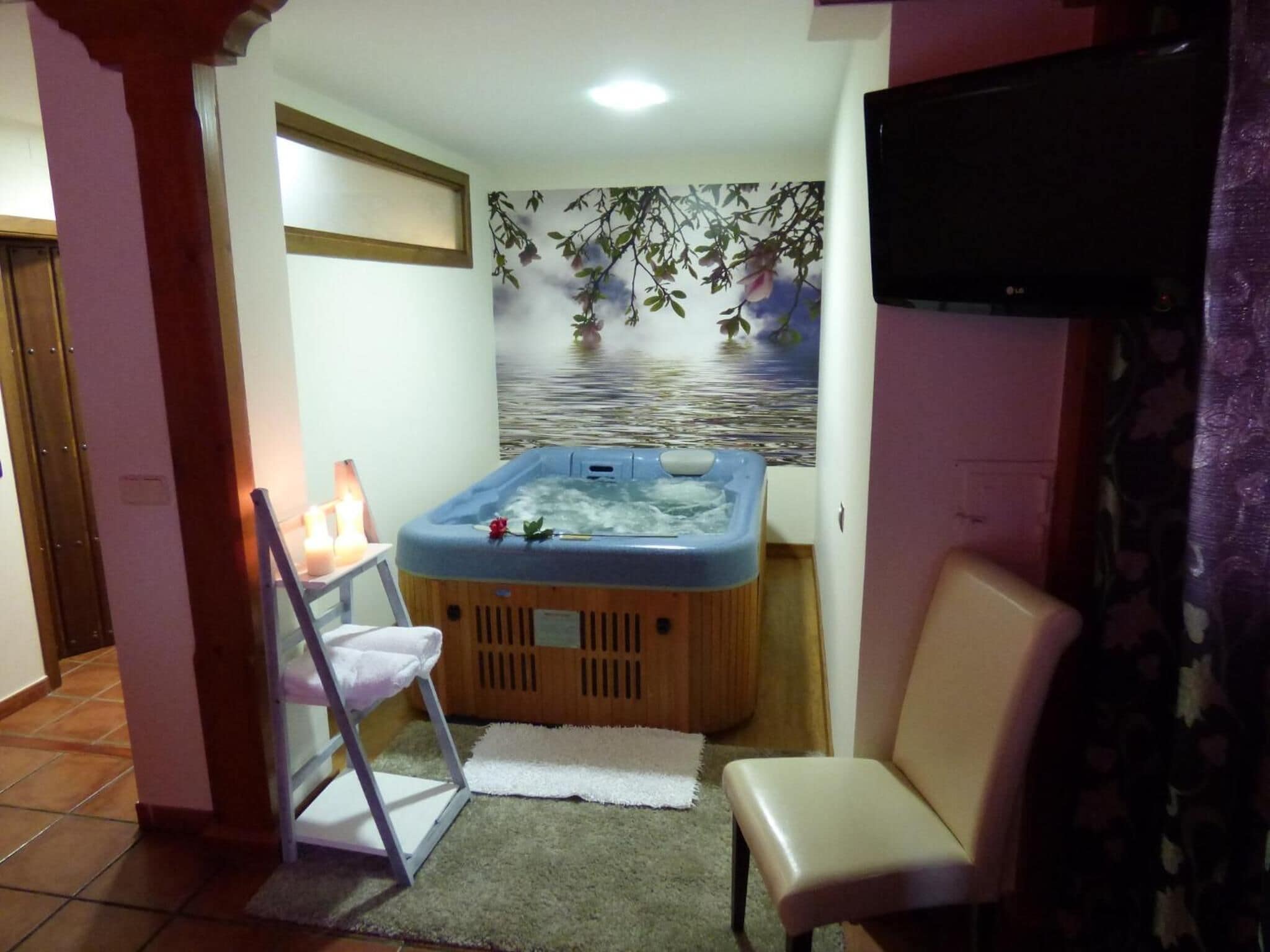 Une petite pièce avec un jacuzzi, une télévision et un fauteuil.